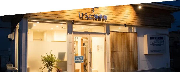 夜間に温かい光が灯る、ひろと接骨院の外観。仕事帰りでも入りやすい落ち着いた雰囲気